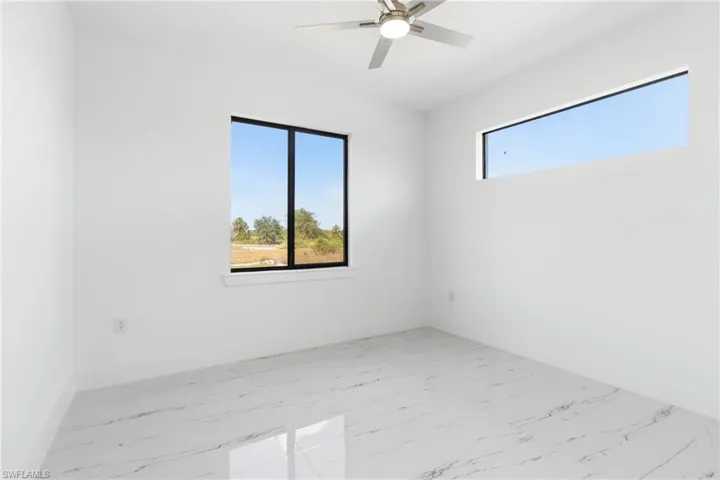Empty room with light marble finish floors and ceiling fan