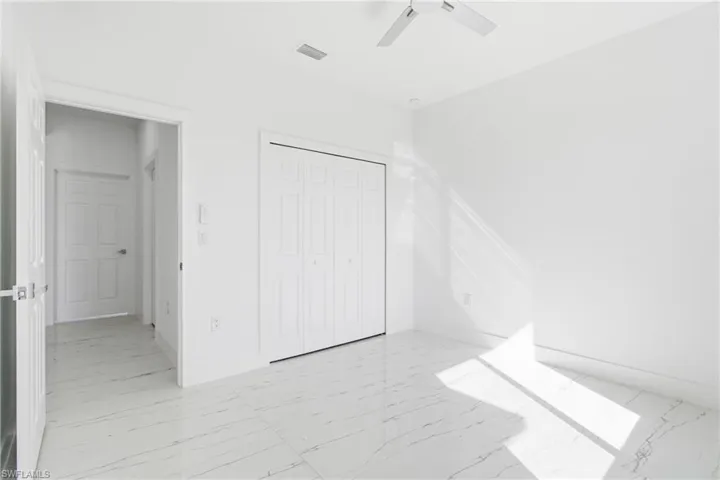 Unfurnished bedroom with light marble finish flooring, a closet, and ceiling fan