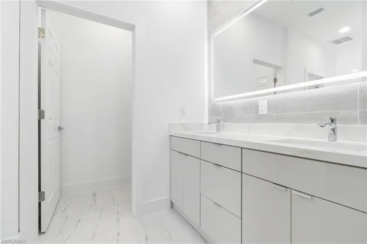 Full bath with double vanity and light marble finish flooring