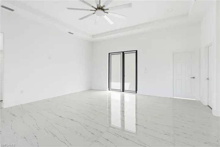 Unfurnished bedroom featuring light marble finish flooring, a ceiling fan, a tray ceiling, and recessed lighting
