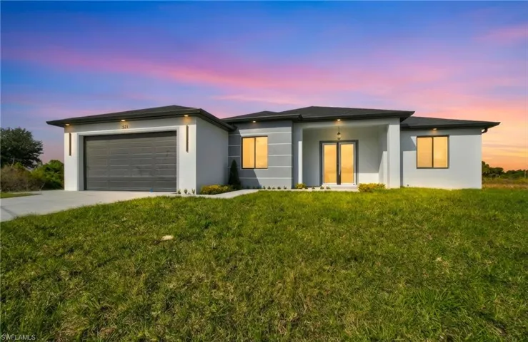 View of front of home with stucco siding, a lawn, concrete driveway, and a garage