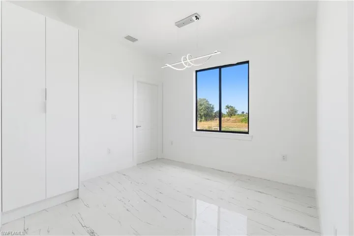 Spare room featuring light marble finish flooring and suspended lighting