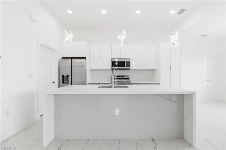 Kitchen featuring white cabinetry, stainless steel appliances, and light stone countertops