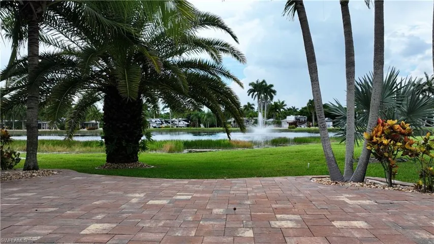 Surrounding community with a lawn, a water view, and a patio