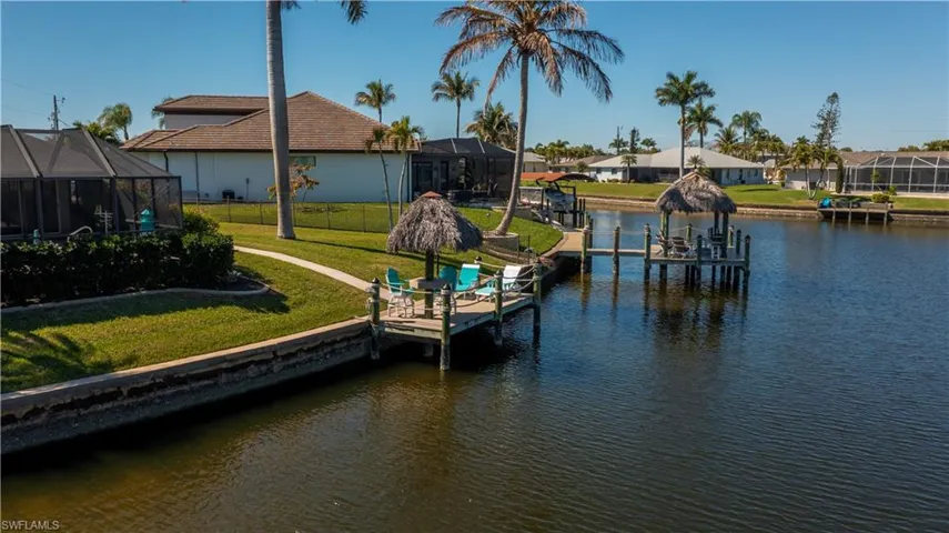 Dock area with a sunroom, boat lift, a lanai, a water view, and a residential view