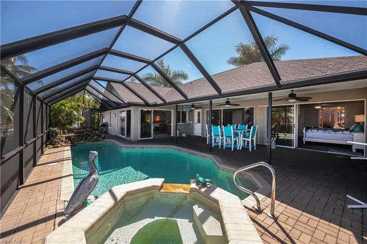 Relaxing pool / spa with a patio, outdoor dining area, a sunroom, and a lanai