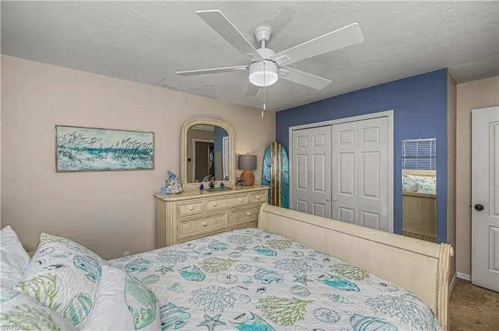 Carpeted bedroom with a ceiling fan and a closet