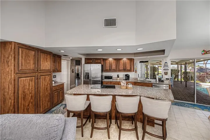Kitchen featuring a breakfast bar area, a high ceiling, recessed lighting, light stone countertops, and stainless steel appliances