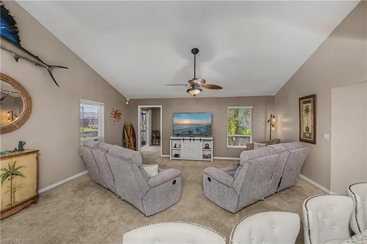 Carpeted living area with vaulted ceiling and a ceiling fan