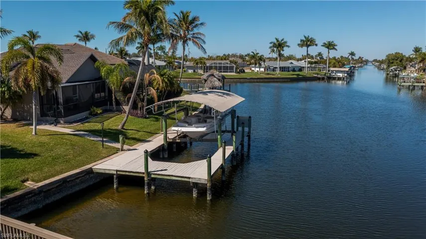 Dock area with a water view, a sunroom, boat lift, a yard, and a residential view