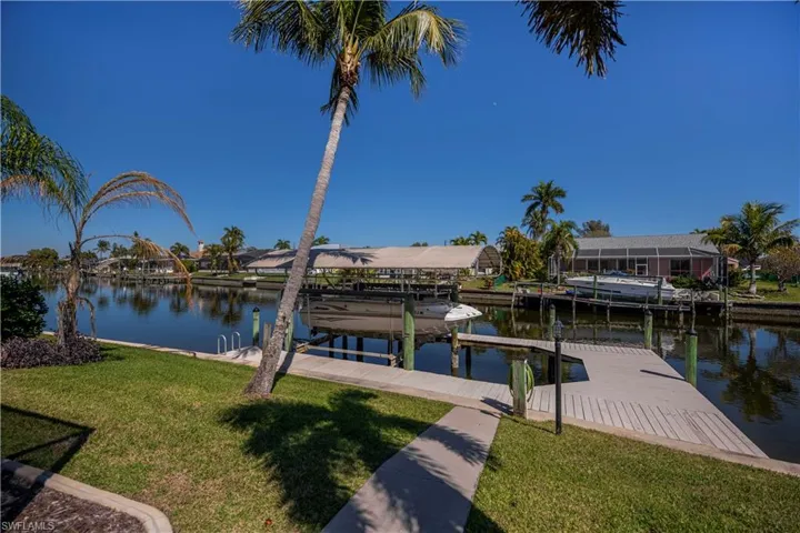 Dock featuring a lawn, boat lift, a water view, and a residential view