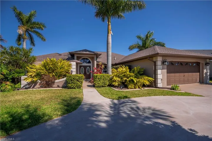 View of front of house with an attached garage, driveway, stucco siding, and a front yard