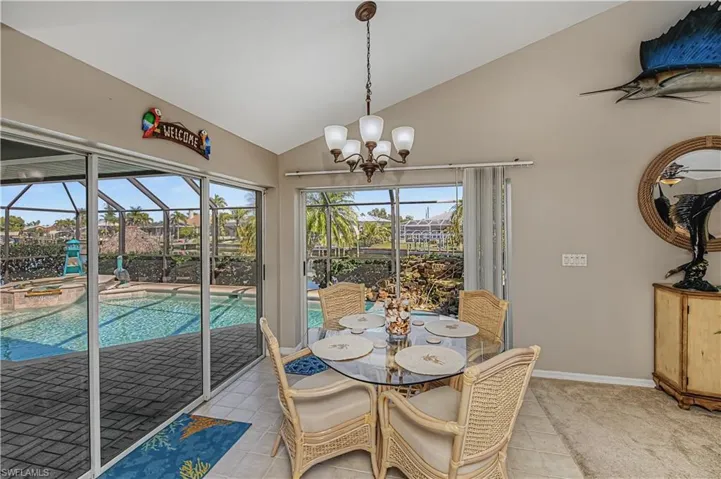 Dining space featuring a sunroom, lofted ceiling, a ceiling fan, light tile patterned flooring, and hanging lights