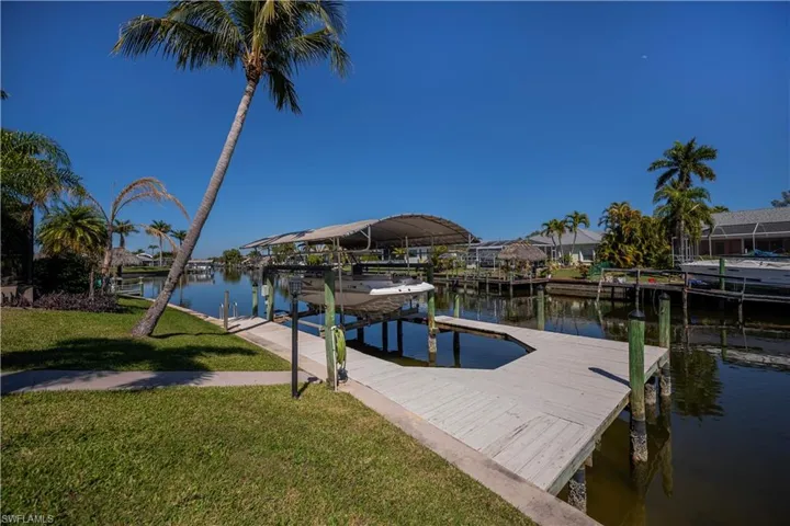 Dock featuring a water view, boat lift, and a yard