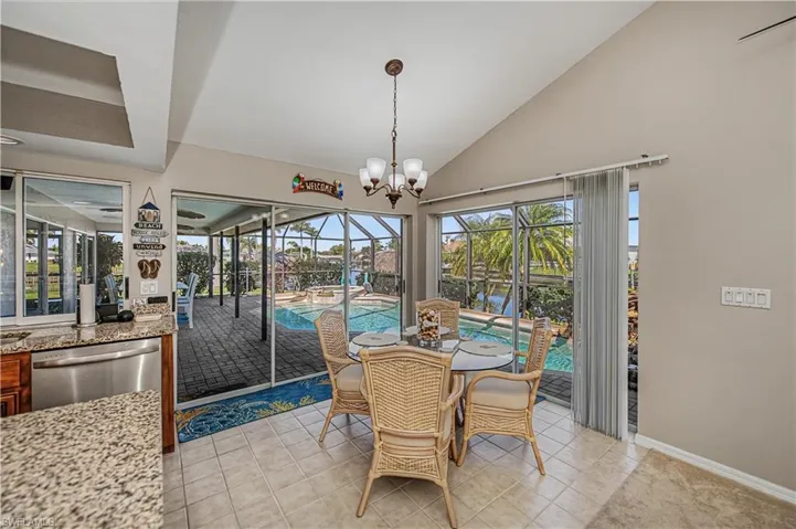 Dining space with a sunroom, lofted ceiling, a chandelier, and light tile patterned floors