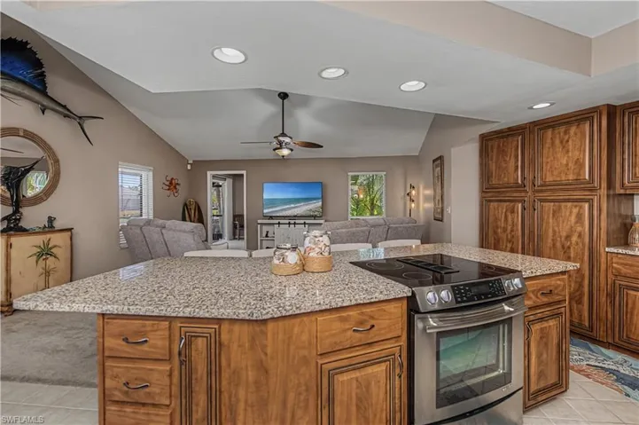 Kitchen with open floor plan, stainless steel electric range, wood finish cabinets, vaulted ceiling, and recessed lighting