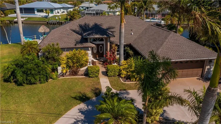 View of front facade featuring a front lawn, a water view, an attached garage, and a shingled roof