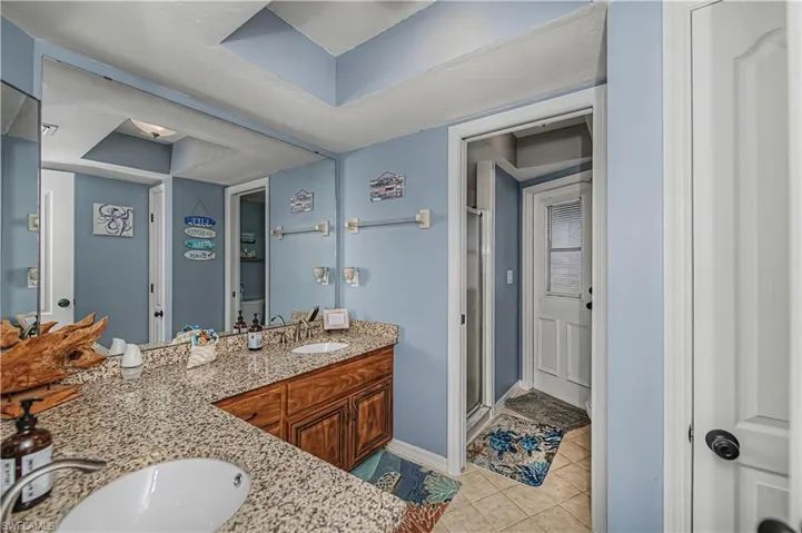Main Bathroom featuring a stall shower, double vanity, and light tile patterned floors