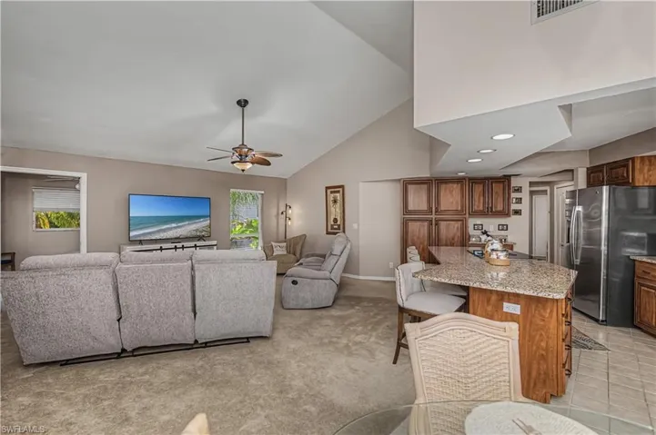 Living area featuring light colored carpet, ceiling fan, vaulted ceiling, and recessed lighting