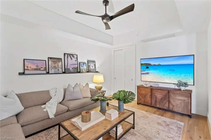 Living room with wood finished floors, a ceiling fan, and a tray ceiling