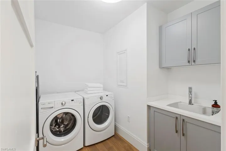 Washroom with washing machine and clothes dryer, dark wood finished floors, and cabinet space