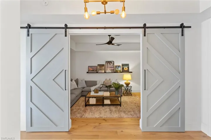 Living area featuring a ceiling fan, a barn door, and wood finished floors