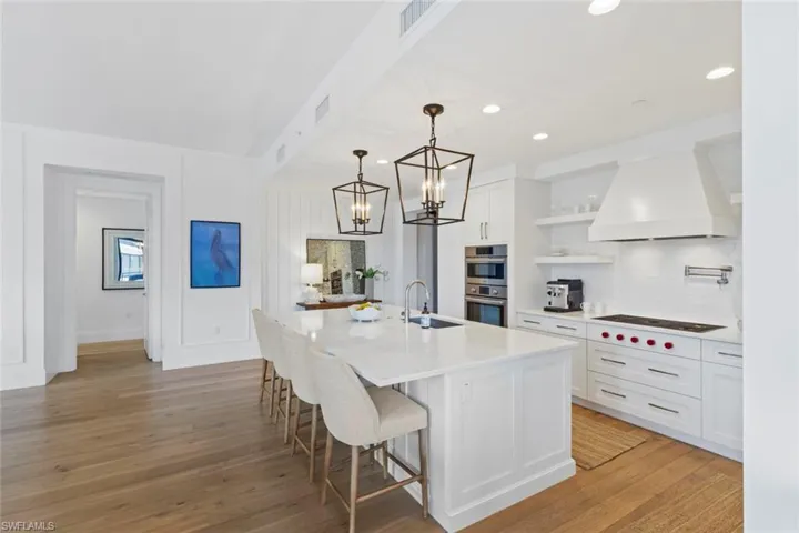 Kitchen featuring backsplash, decorative light fixtures, white cabinetry, a breakfast bar area, and recessed lighting
