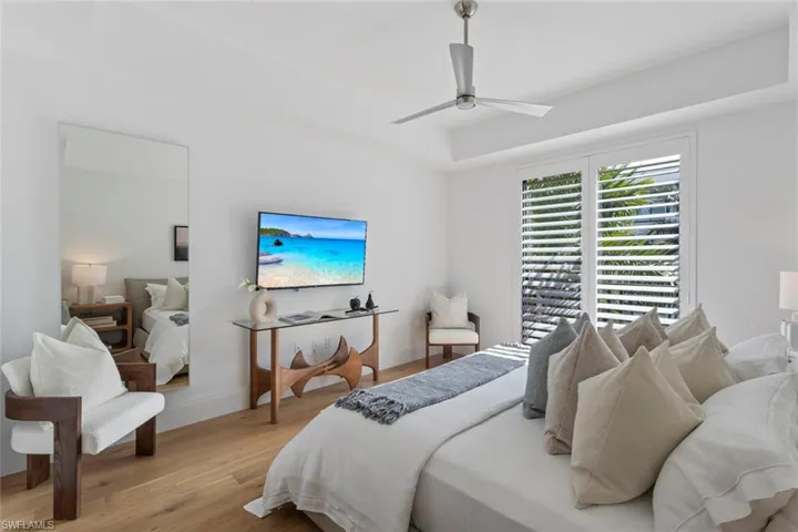 Bedroom with wood finished floors, a ceiling fan, and a tray ceiling