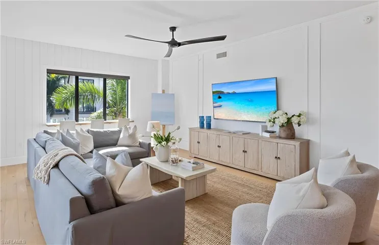 Living room with light wood-type flooring, a decorative wall, and ceiling fan