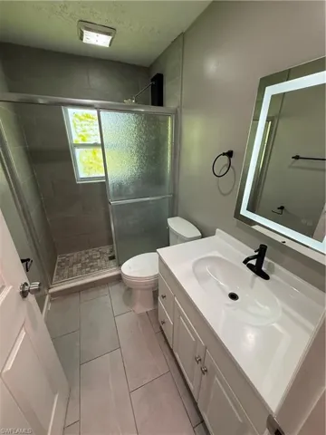 Bathroom with vanity, a stall shower, and light tile patterned flooring