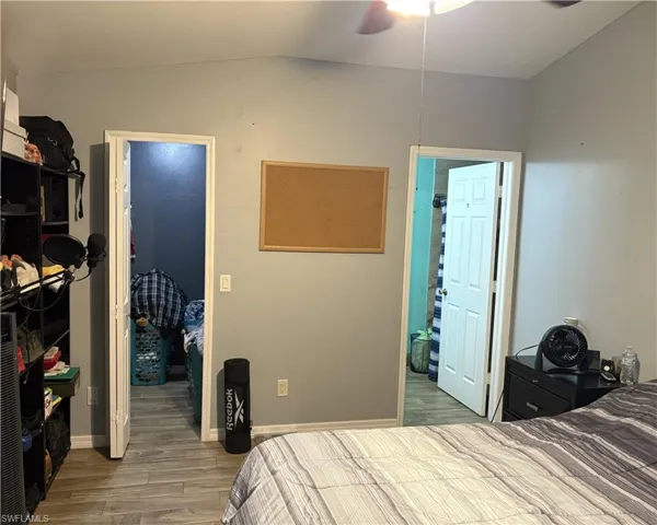 Bedroom featuring a spacious closet, wood finished floors, a ceiling fan, and vaulted ceiling