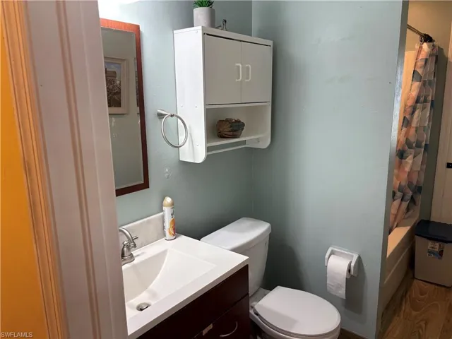 Full bath featuring vanity, shower / bath combo, and wood finished floors
