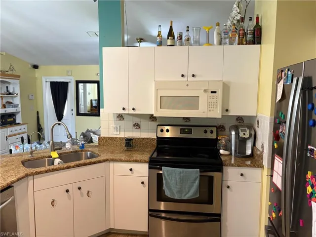 Kitchen featuring appliances with stainless steel finishes, white cabinetry, and tasteful backsplash