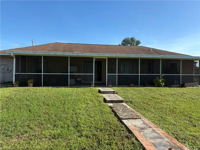 View of front of house featuring a sunroom, a shingled roof, and a front yard