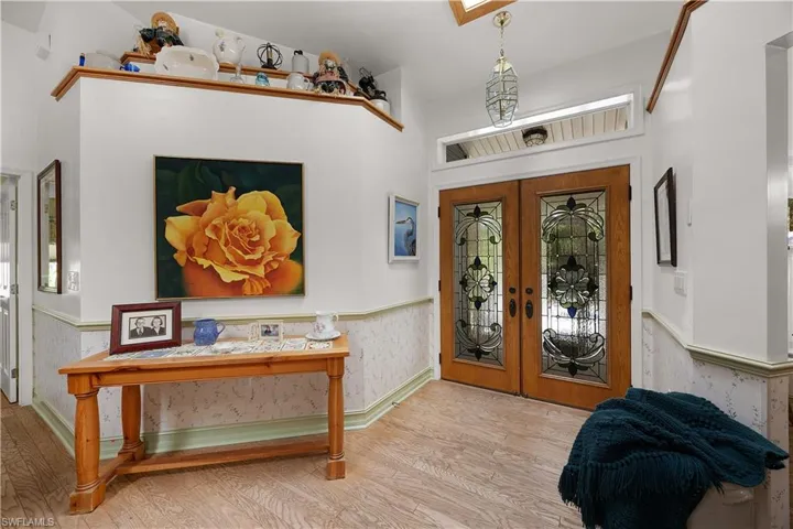Foyer with french doors, wood finished floors, a wainscoted wall, and wallpapered walls