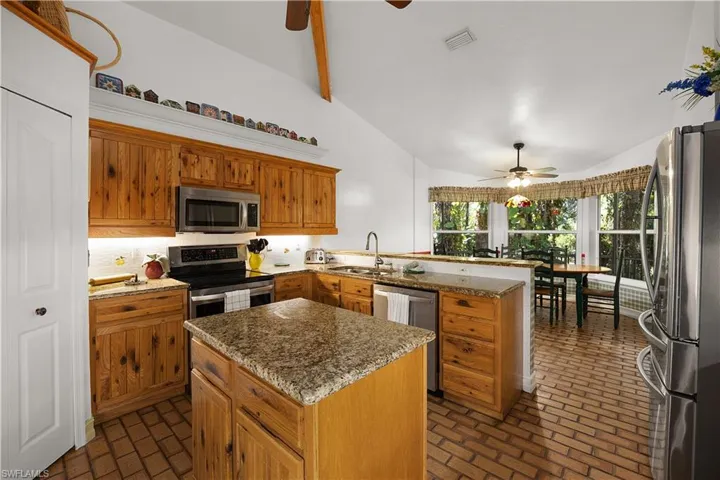 Kitchen featuring ceiling fan, a peninsula, stainless steel appliances, wood finish cabinets, and a kitchen island