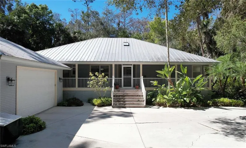 View of front of property featuring a metal roof, concrete driveway, a porch, and a garage