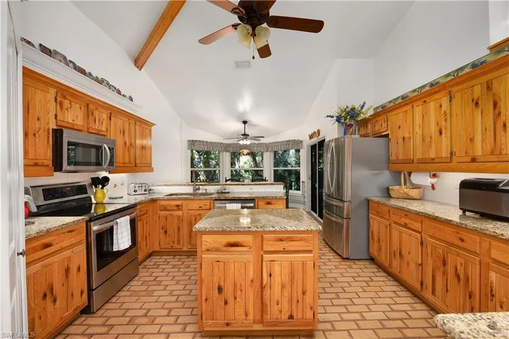 Kitchen featuring stainless steel appliances, decorative backsplash, ceiling fan, a kitchen island, and a peninsula