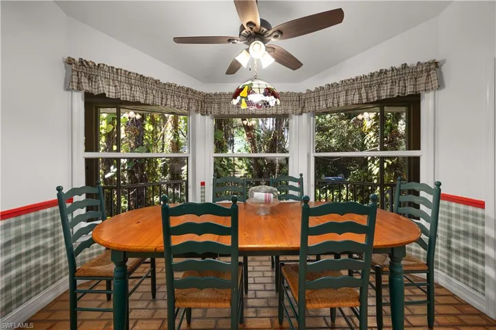 Dining area featuring wallpapered walls, brick patterned floors, ceiling fan, vaulted ceiling, and wainscoting
