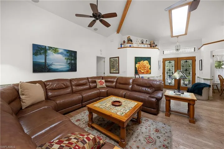 Living room featuring french doors, light wood-type flooring, a ceiling fan, and vaulted ceiling