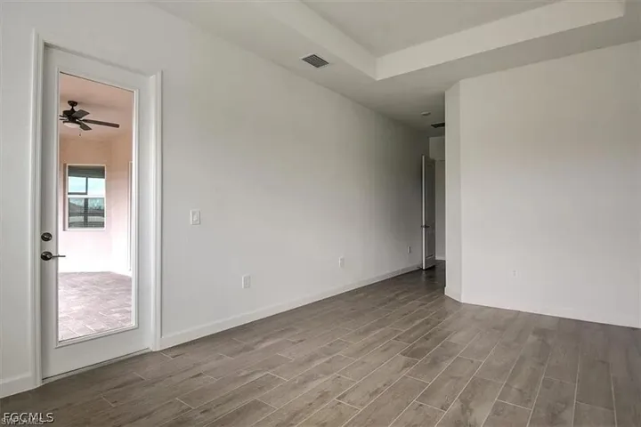 Spacious interior room featuring wood-finish tile flooring, a tray ceiling, and fresh white walls