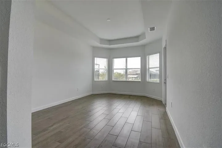 Spacious room featuring wood-finish flooring and a tray ceiling