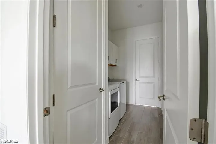 Dedicated laundry area featuring wood-finish flooring, white cabinetry, and recessed lighting