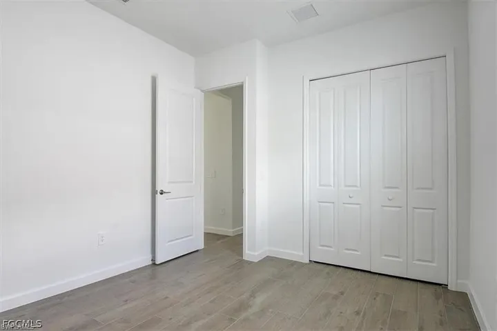 Room featuring light wood-finish flooring, white walls, and a white bi-fold closet door