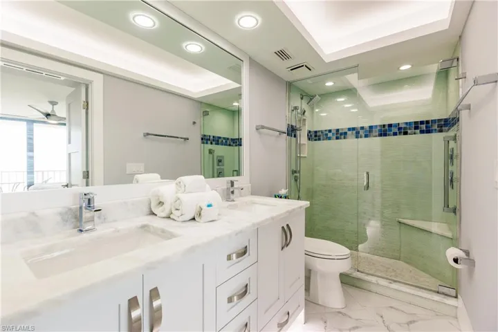 Full bath with a stall shower, double vanity, and recessed lighting