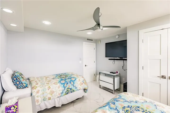 Bedroom featuring ceiling fan, light marble finish flooring, and recessed lighting