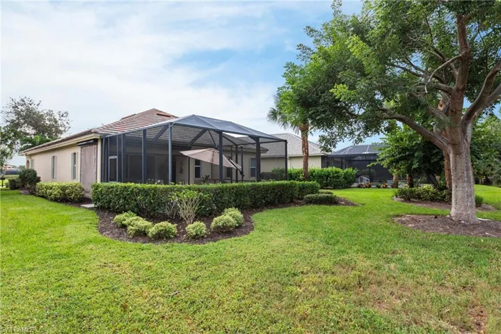 View of green lawn with a lanai and a sunroom
