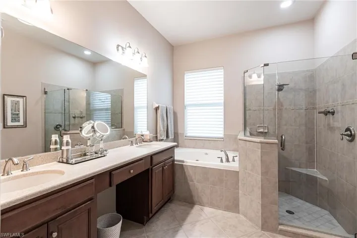 Bathroom with double vanity, a stall shower, a bath, and light tile patterned floors