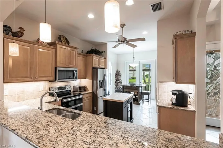 Kitchen featuring light stone countertops, decorative light fixtures, stainless steel appliances, tasteful backsplash, and recessed lighting