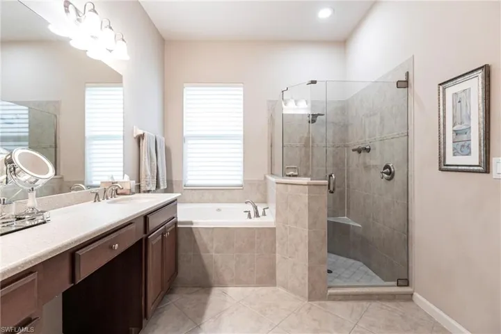 Bathroom featuring vanity, a bath, a shower stall, and light tile patterned flooring